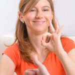 A Woman Sitting On The Sofa Making Sign Language.